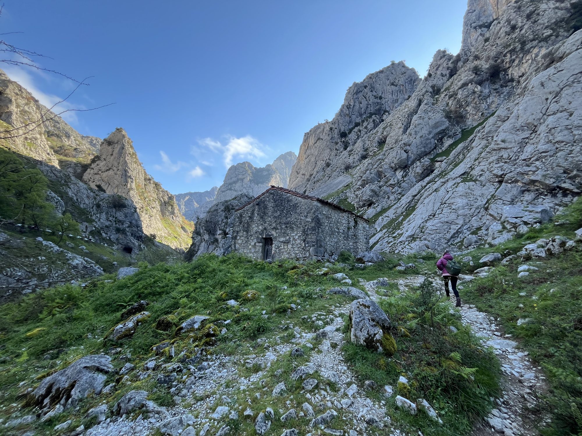 El desfiladero del Cares, con una cabaña de piedra y una caminante en el sendero